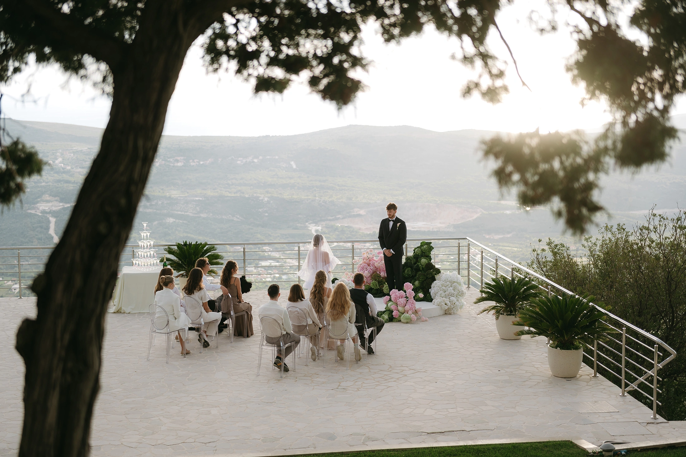 Flottie The Cabbage Affair wedding decor and organisation: modern ceremony setup featuring transparent ghost chairs and a unique sculptural altar installation made of fresh cabbages and pink and white florals overlooking a mountain view