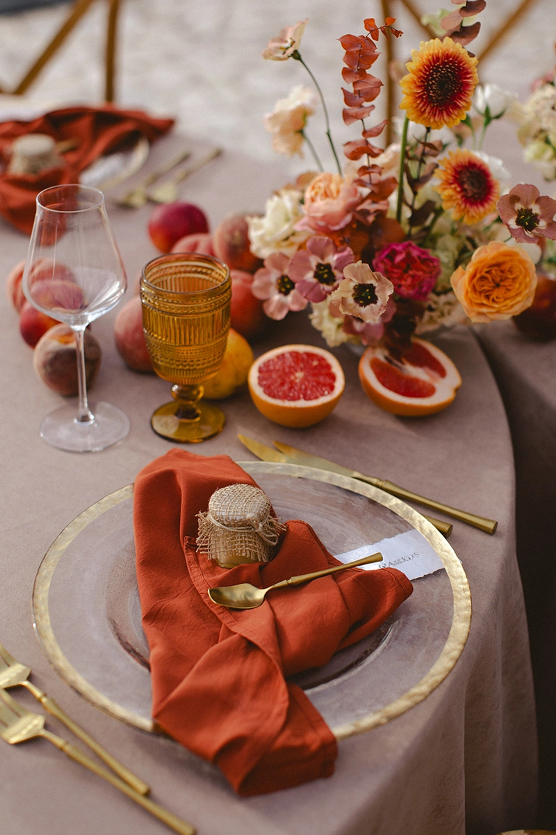 Flottie Peach Haze wedding decor and organisation: close-up of a delicate floral centerpiece arrangement with pastel roses and fresh peaches on a table
