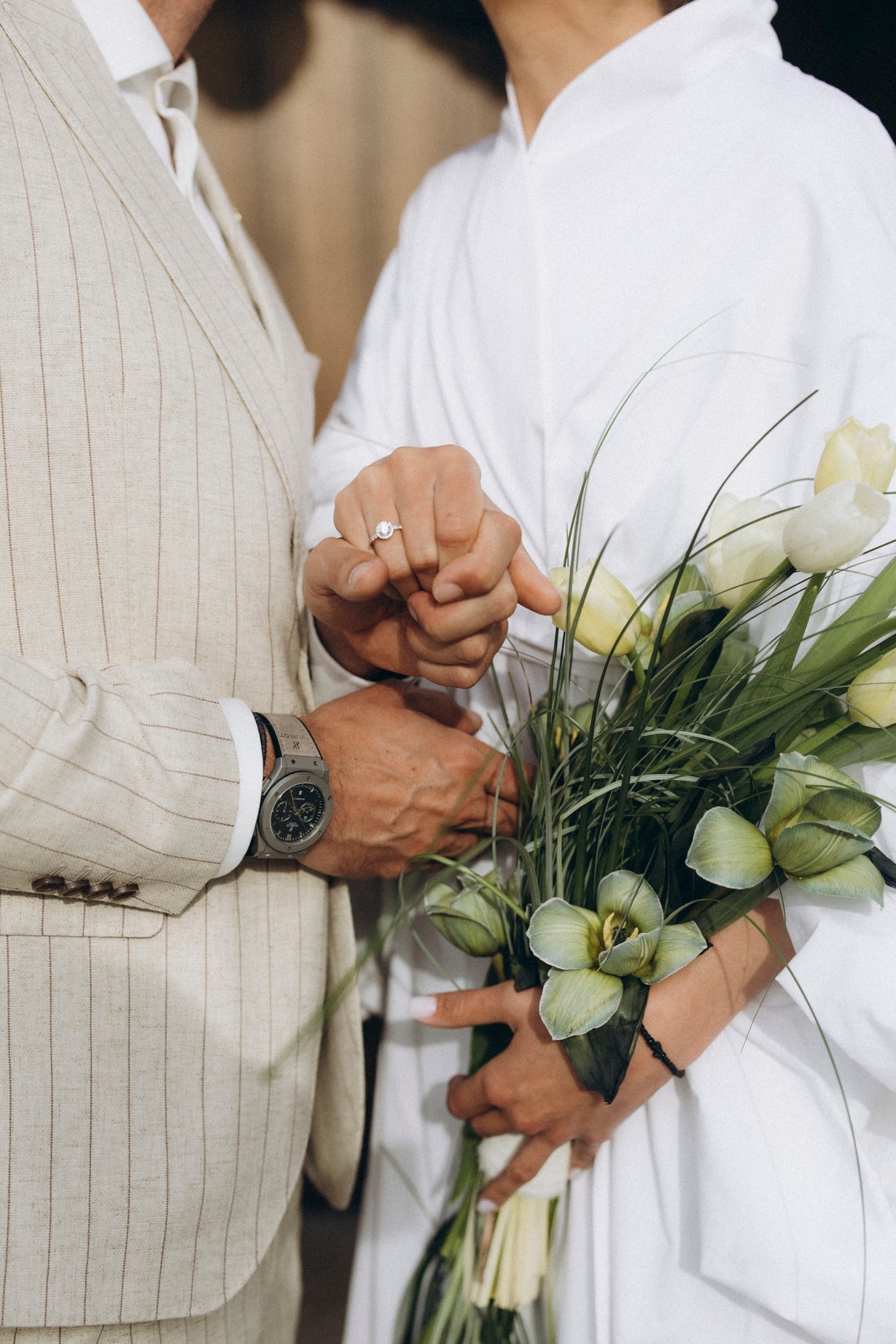 Flottie flower decor, wedding, and organisation at Borgo Lapis in Croatia: close-up of bride and groom showing wedding rings alongside a bespoke floral bouquet