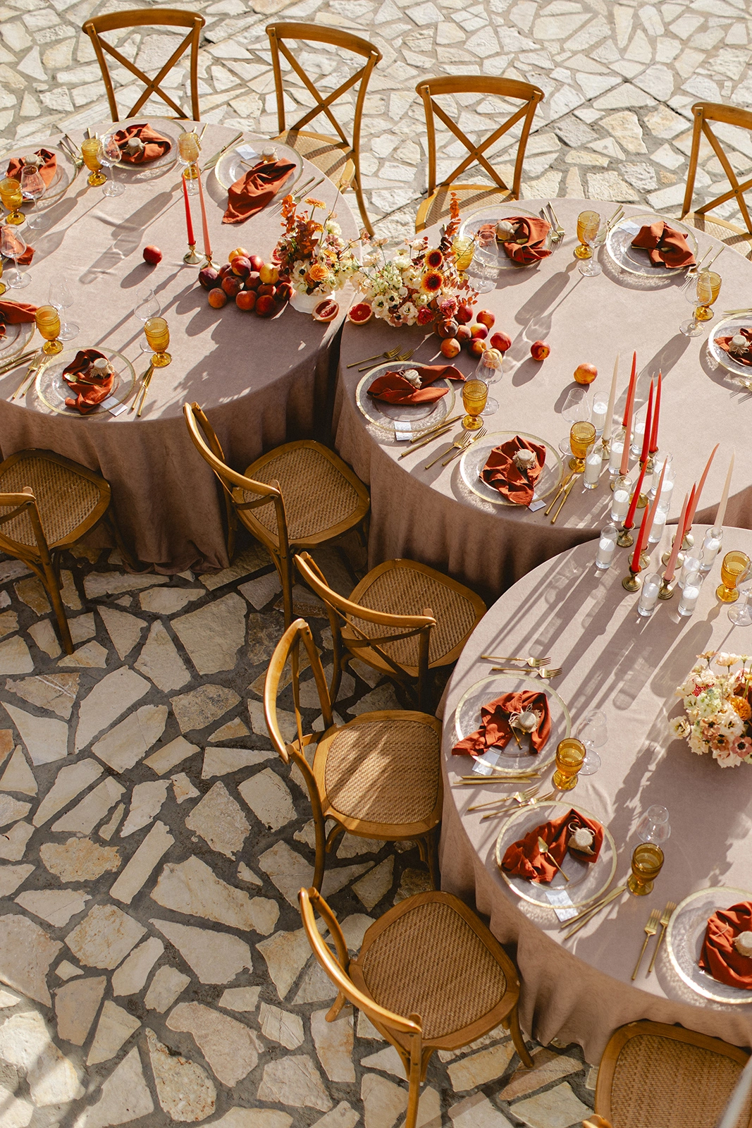 Flottie Peach Haze wedding decor and organisation: aerial view of guests enjoying an outdoor wedding reception dinner at round tables styled with peach-toned florals and candles