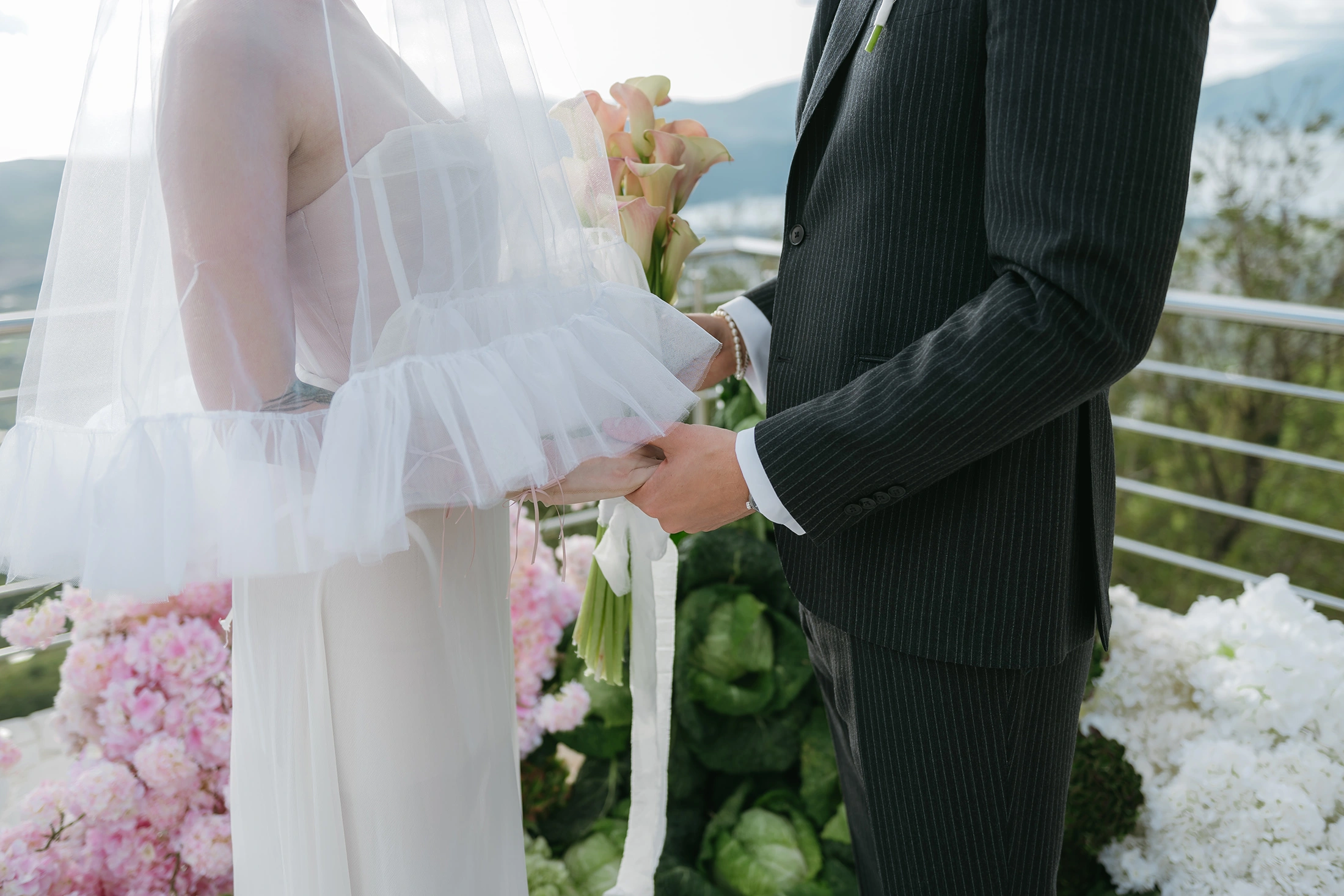 Flottie The Cabbage Affair wedding decor and organisation: close-up portrait of a bride in a tulle dress with black ribbons gently touching exotic anthurium flowers and gerberas at a candlelit evening reception table