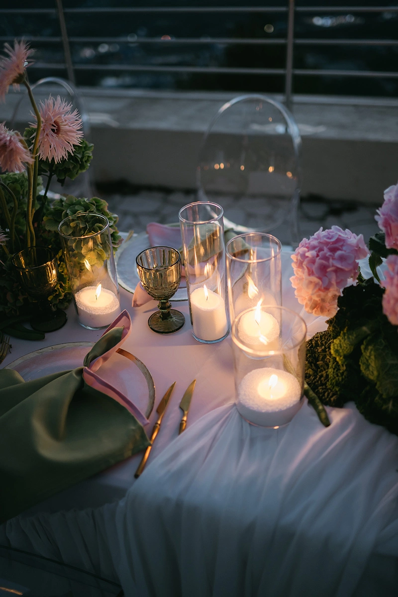 Flottie The Cabbage Affair wedding decor and organisation: close-up of an upscale reception table center-piece featuring fresh heads of cabbage, pastel anthuriums, gerberas, and glowing candles in glass cylinders