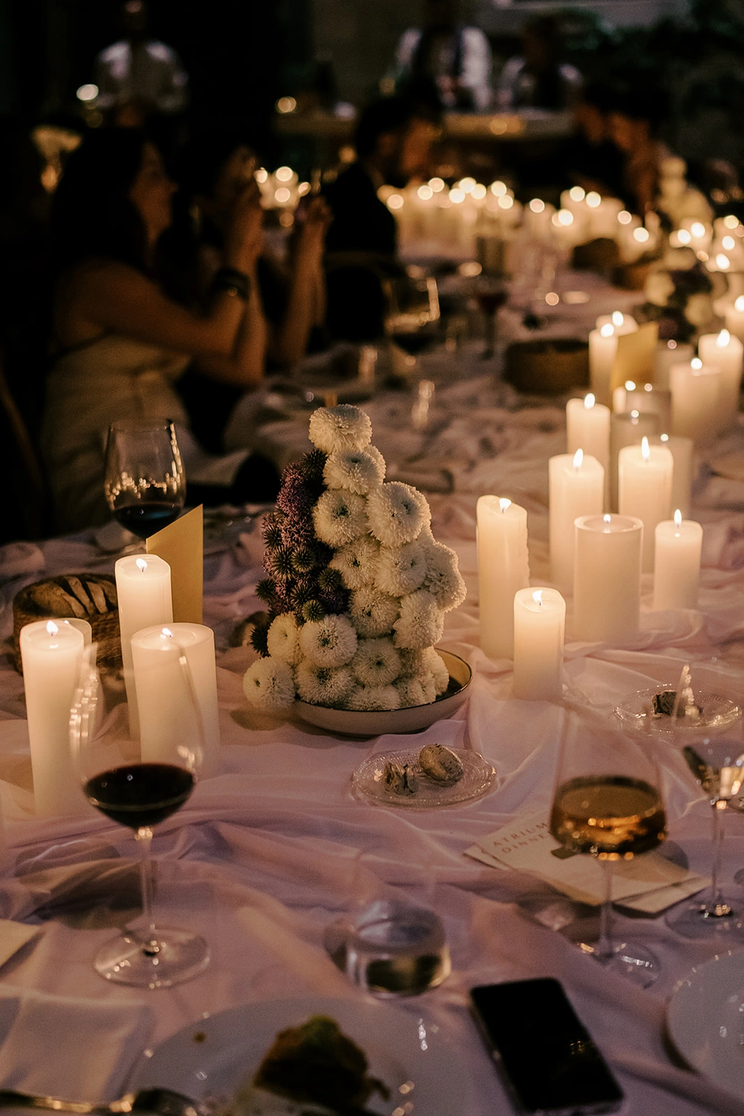 Flottie wedding decor and organisation: close-up of an elegant candlelit wedding tablescape featuring white flower arrangements, wine glasses, and refined place settings