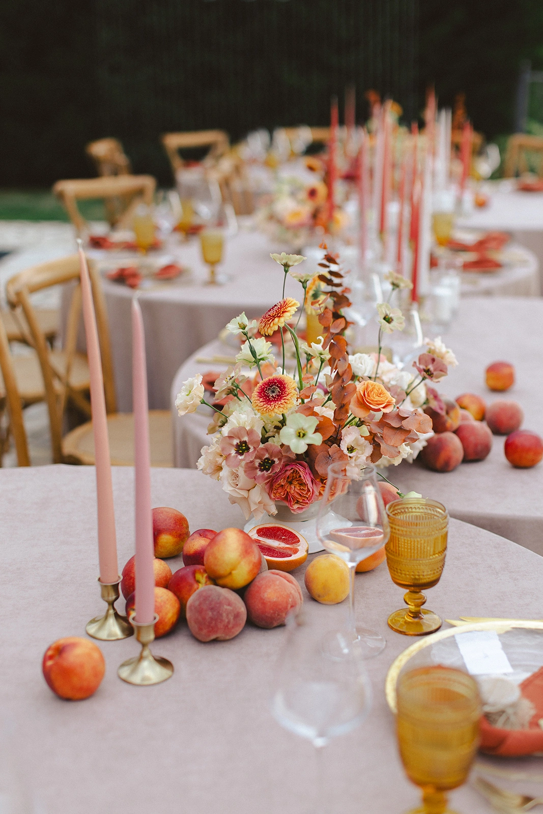 Flottie Peach Haze wedding decor and organisation: close-up of a delicate floral centerpiece arrangement with pastel roses and fresh peaches on a table