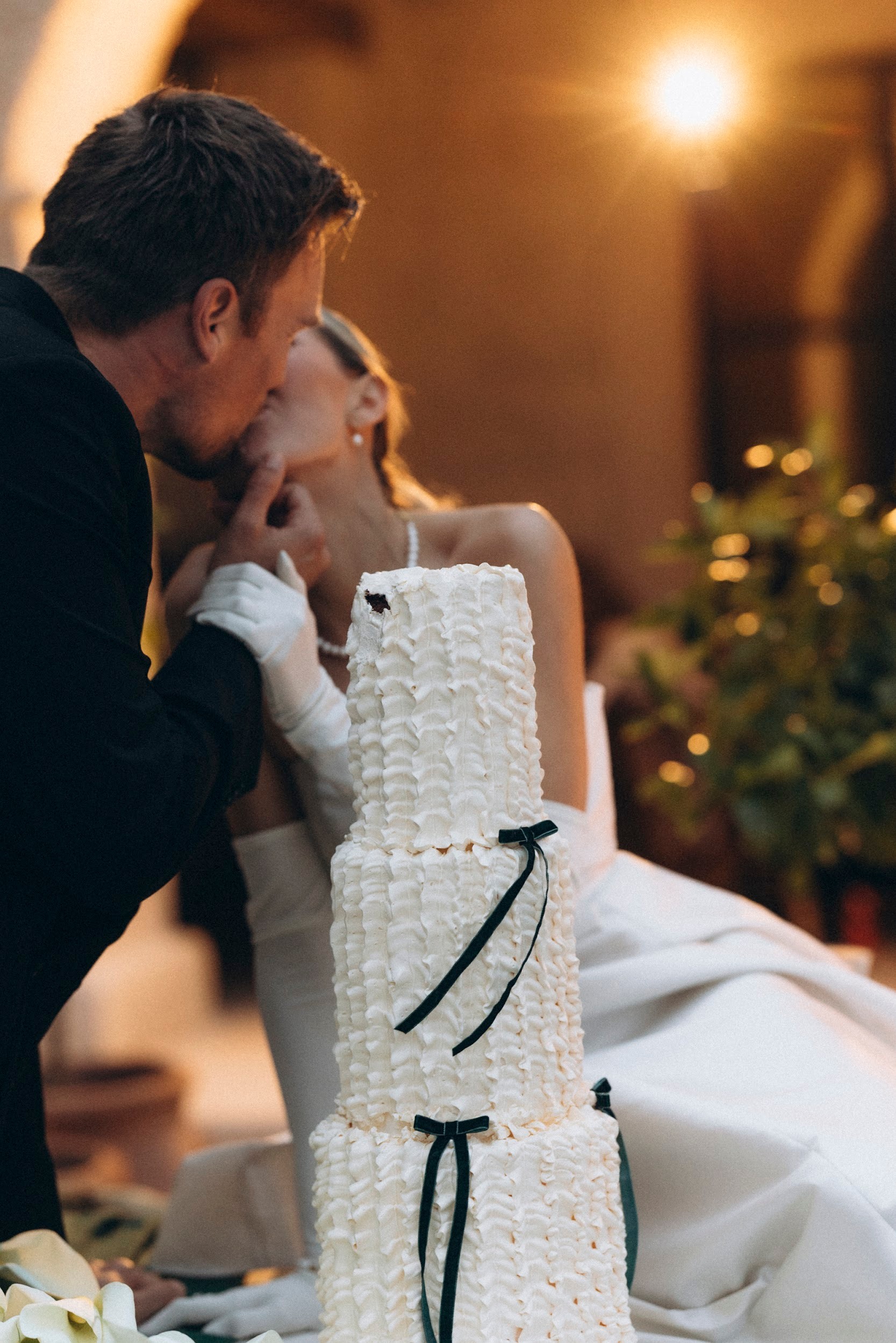 Flottie flower decor, wedding, and organisation at Borgo Lapis in Croatia: bride and groom playfully cutting a tiered wedding cake adorned with white calla lilies and rich green drapery