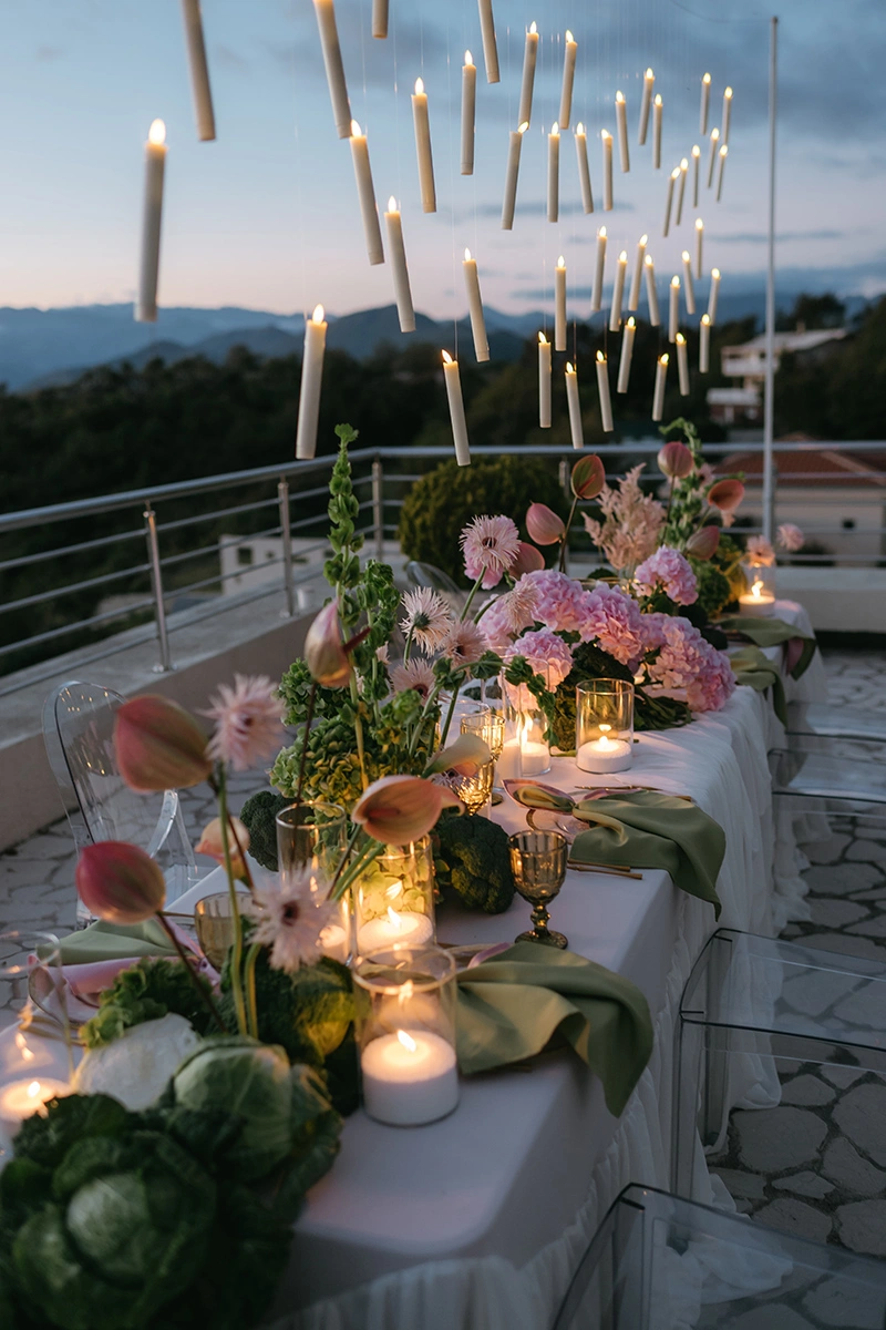 Flottie The Cabbage Affair wedding decor and organisation: close-up of an upscale reception table center-piece featuring fresh heads of cabbage, pastel anthuriums, gerberas, and glowing candles in glass cylinders