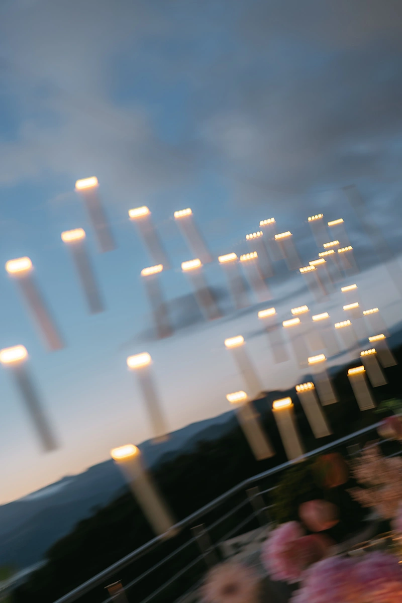 Flottie The Cabbage Affair wedding decor and organisation: bride and groom sharing a tender kiss at twilight beneath a suspended canopy of floating candles against an evening sky