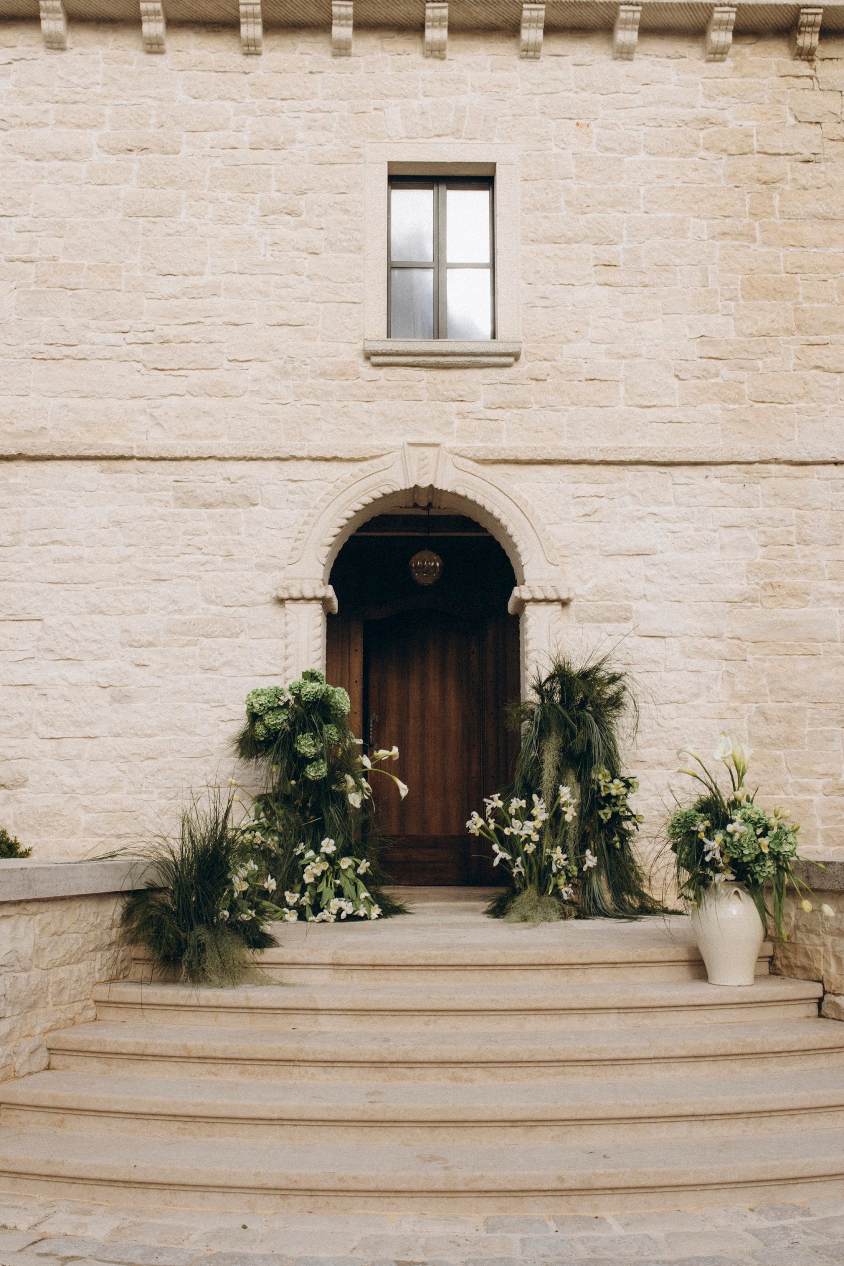 Flottie flower decor, wedding, and organisation at Borgo Lapis in Croatia: couple exchanging vows surrounded by lush green hydrangea and white floral installations against stone architecture