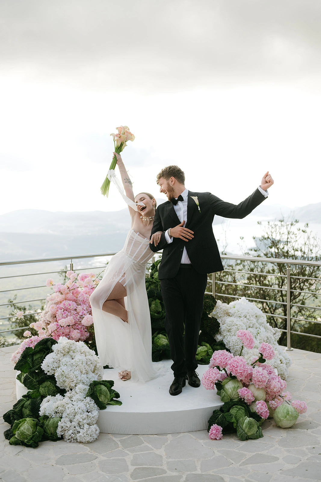 Flottie The Cabbage Affair wedding decor and organisation: enthusiastic bride holding a modern bouquet and groom celebrating joyfully together on stage amid creative floral and cabbage arrangements