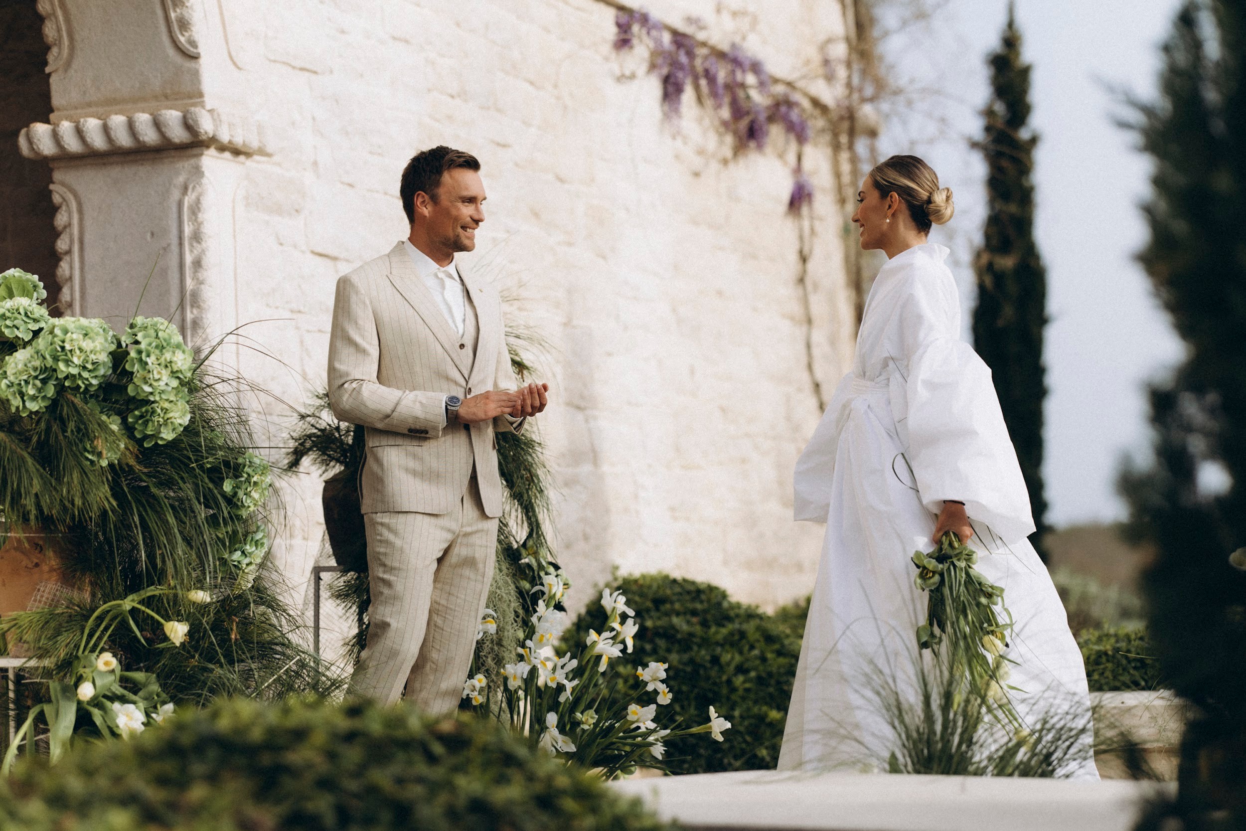 Flottie flower decor, wedding, and organisation at Borgo Lapis in Croatia: couple exchanging vows surrounded by lush green hydrangea and white floral installations against stone architecture