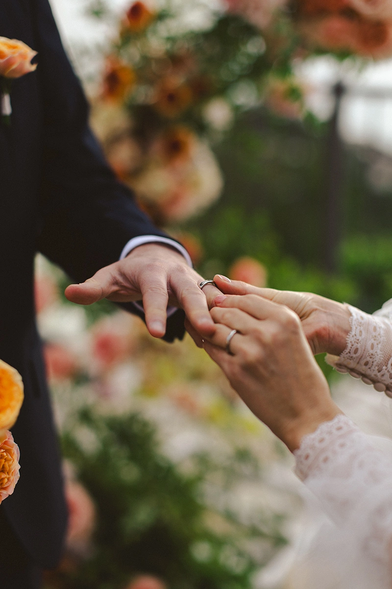 Flottie Peach Haze wedding decor and organisation: bride and groom posing together under a draped archway framed by vibrant peach and pink floral arrangements