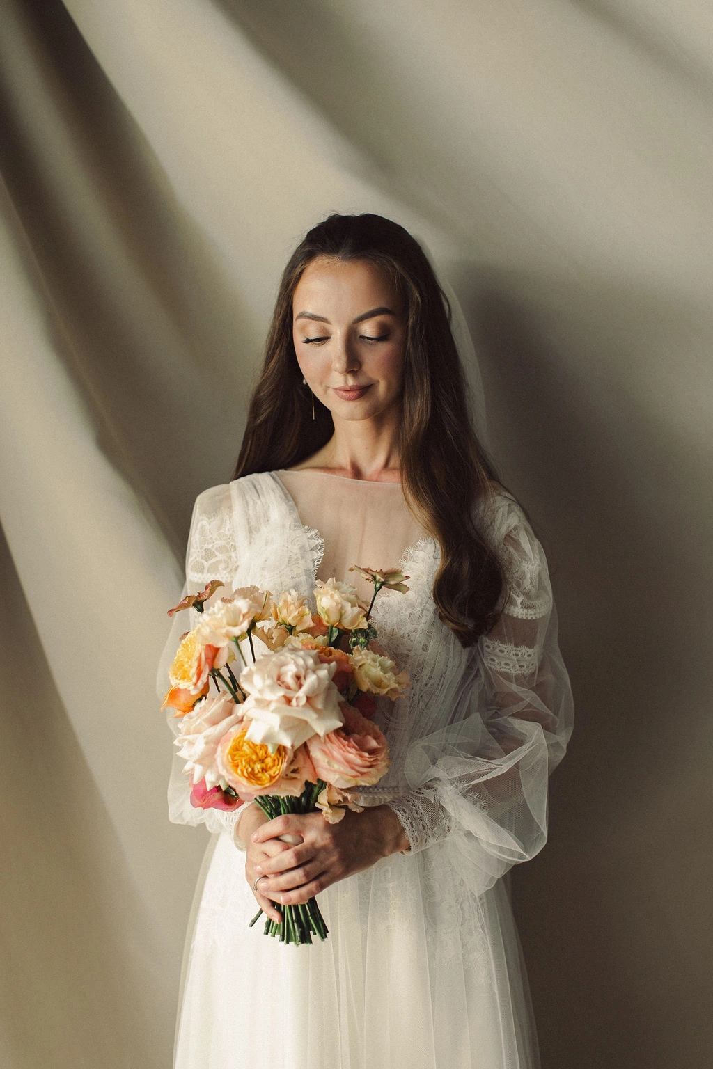 Flottie Peach Haze wedding decor and organisation: portrait of a bride in a lace gown holding a custom peach and pastel bridal bouquet