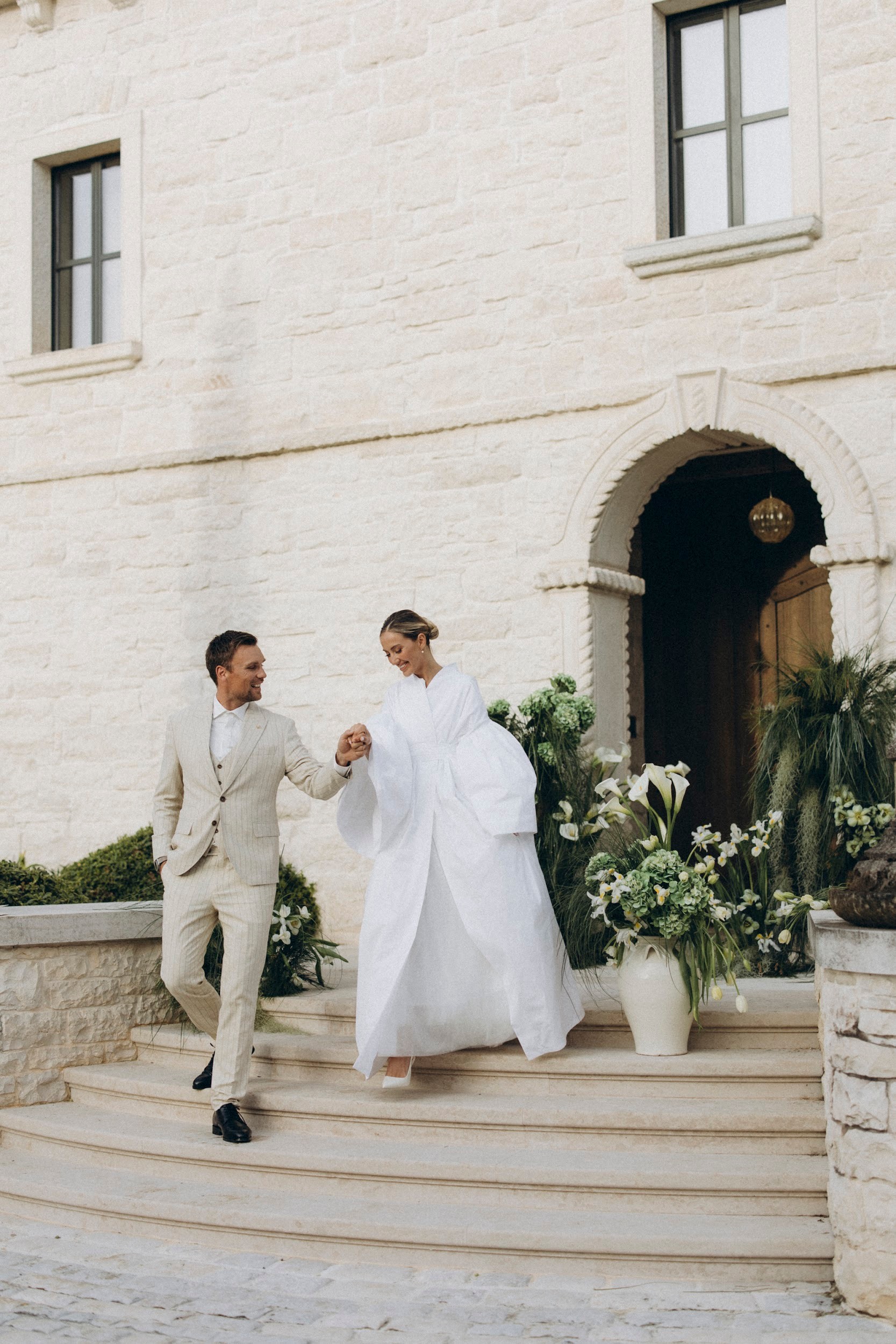 Flottie flower decor, wedding, and organisation at Borgo Lapis in Croatia: couple exchanging vows surrounded by lush green hydrangea and white floral installations against stone architecture